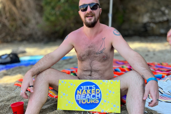 a person sitting at a beach umbrella in the sand